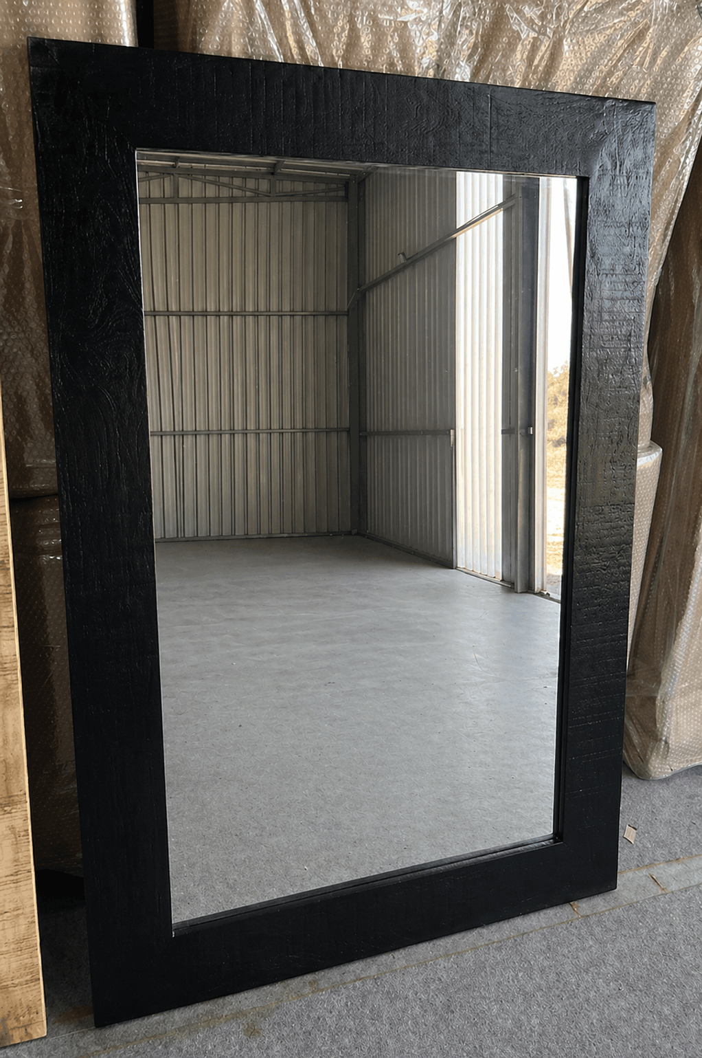 Black wood-framed wall mirror with textured finish