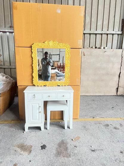 Yellow-framed mirror on a white cabinet with cardboard boxes in the background