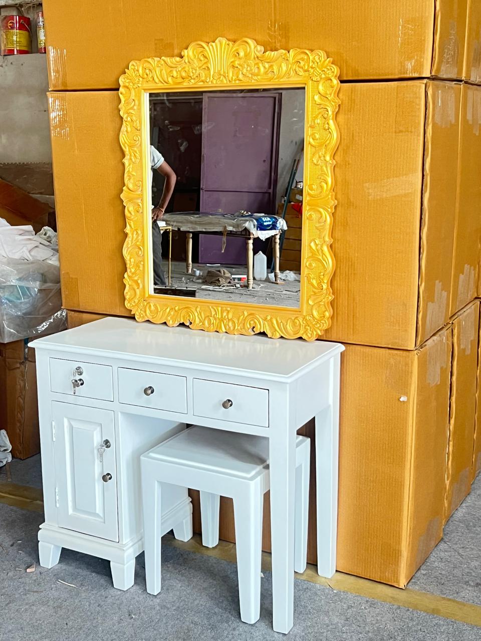 White vanity with yellow-framed mirror against a backdrop of stacked boxes.