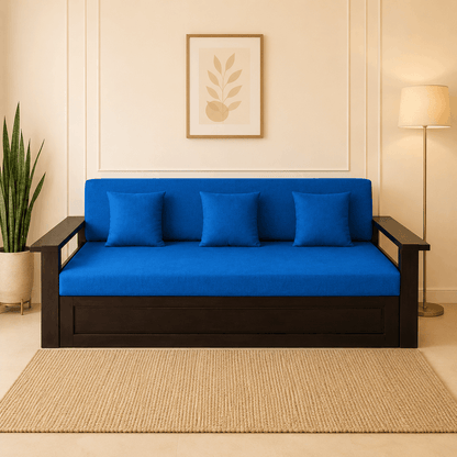 Blue futon sofa with black frame in a room with a plant and lamp.
