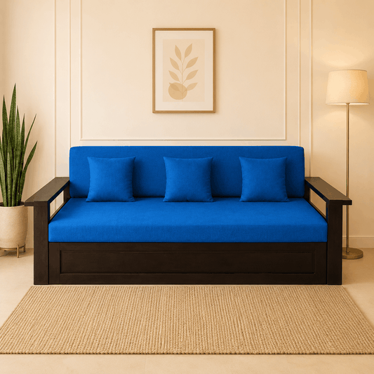 Blue futon sofa with black frame in a room with a plant and lamp.