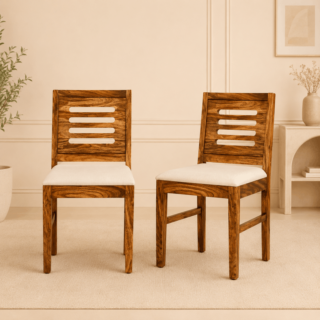 Two wooden chairs with white cushions in a room with beige walls and a small table.
