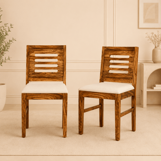 Two wooden chairs with white cushions in a room with beige walls and a small table.
