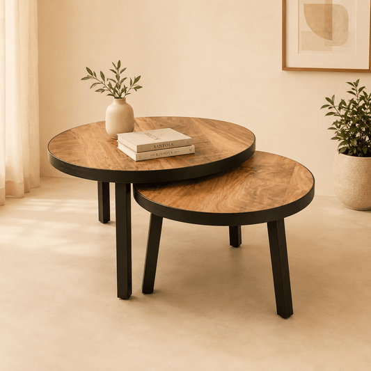 Two wooden coffee tables with a plant and books in a room with beige walls and a framed picture.