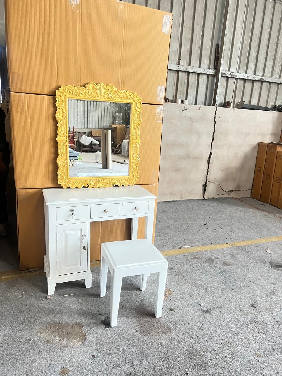 White vanity table with yellow-framed mirror and white stool in an outdoor setting.