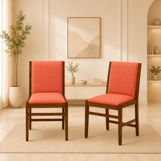 Two chairs with red cushions in a room with a plant and wall art.