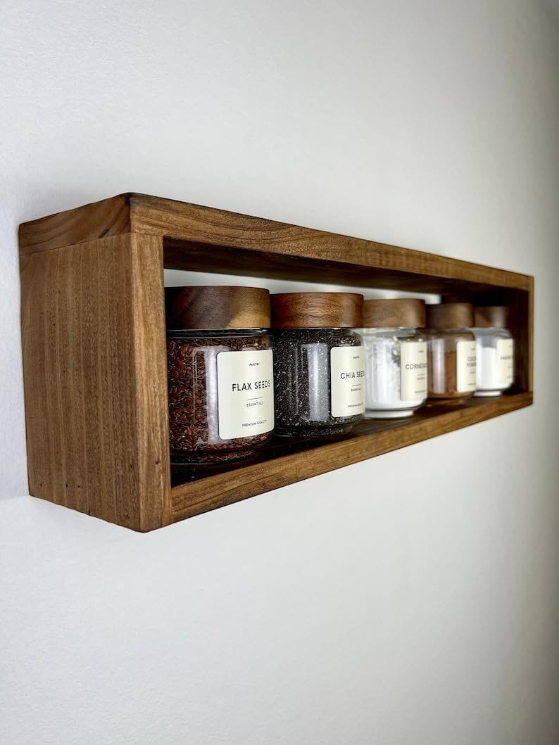 Wooden shelf with various jars on a white wall