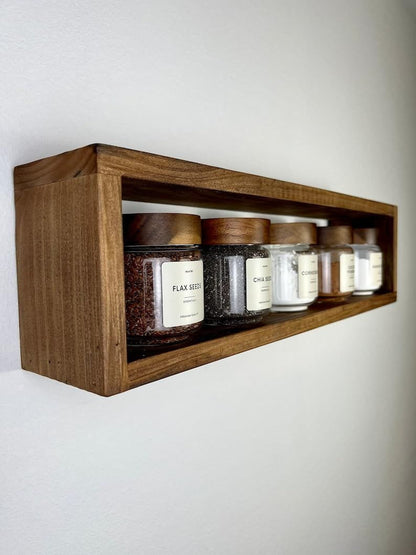 Wooden shelf with various jars on a white wall
