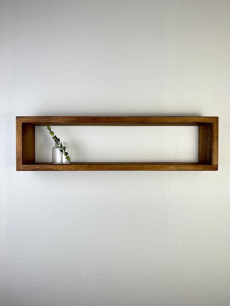 Wooden shelf with a small plant on a plain wall
