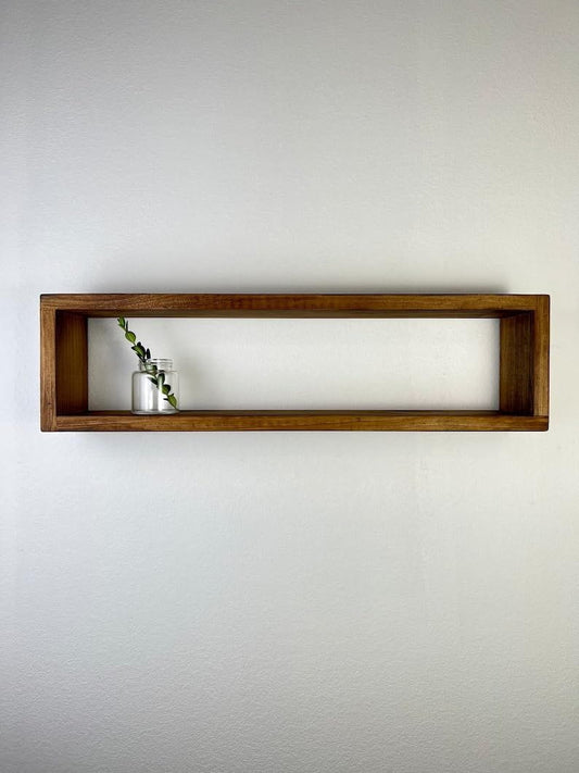 Wooden shelf with a small plant on a plain wall